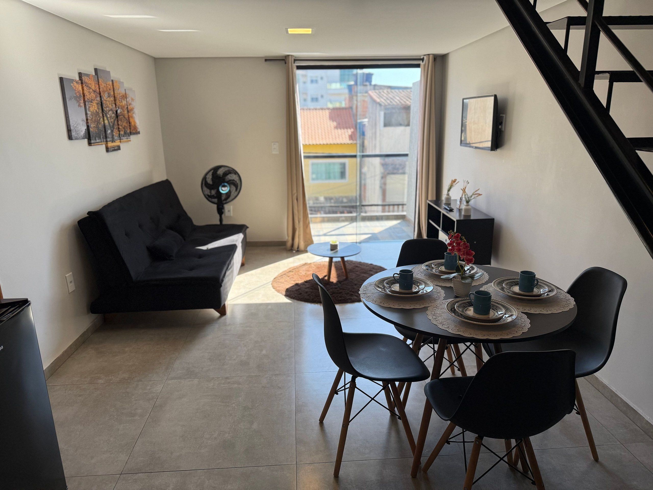 Een moderne woonkamer met een bank, eettafel, stoelen en een ventilator.