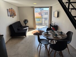 Una sala moderna con un sofá, mesa de comedor, sillas y un ventilador.