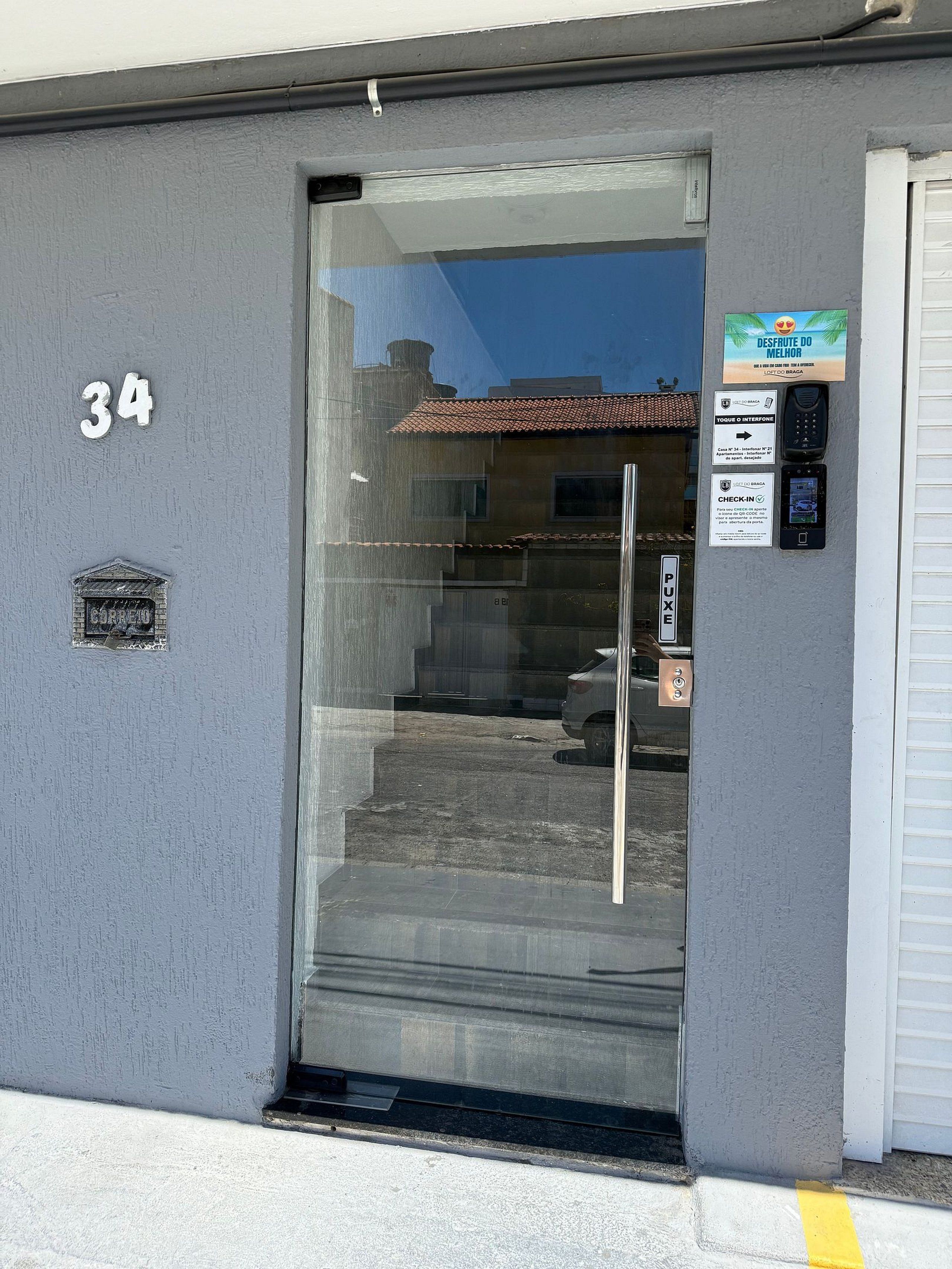 Una entrada de edificio con puerta de cristal, buzón y el número 34 en la pared.