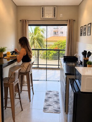 Una cucina moderna con un'ampia finestra, una zona pranzo con due sgabelli e un forno a microonde.