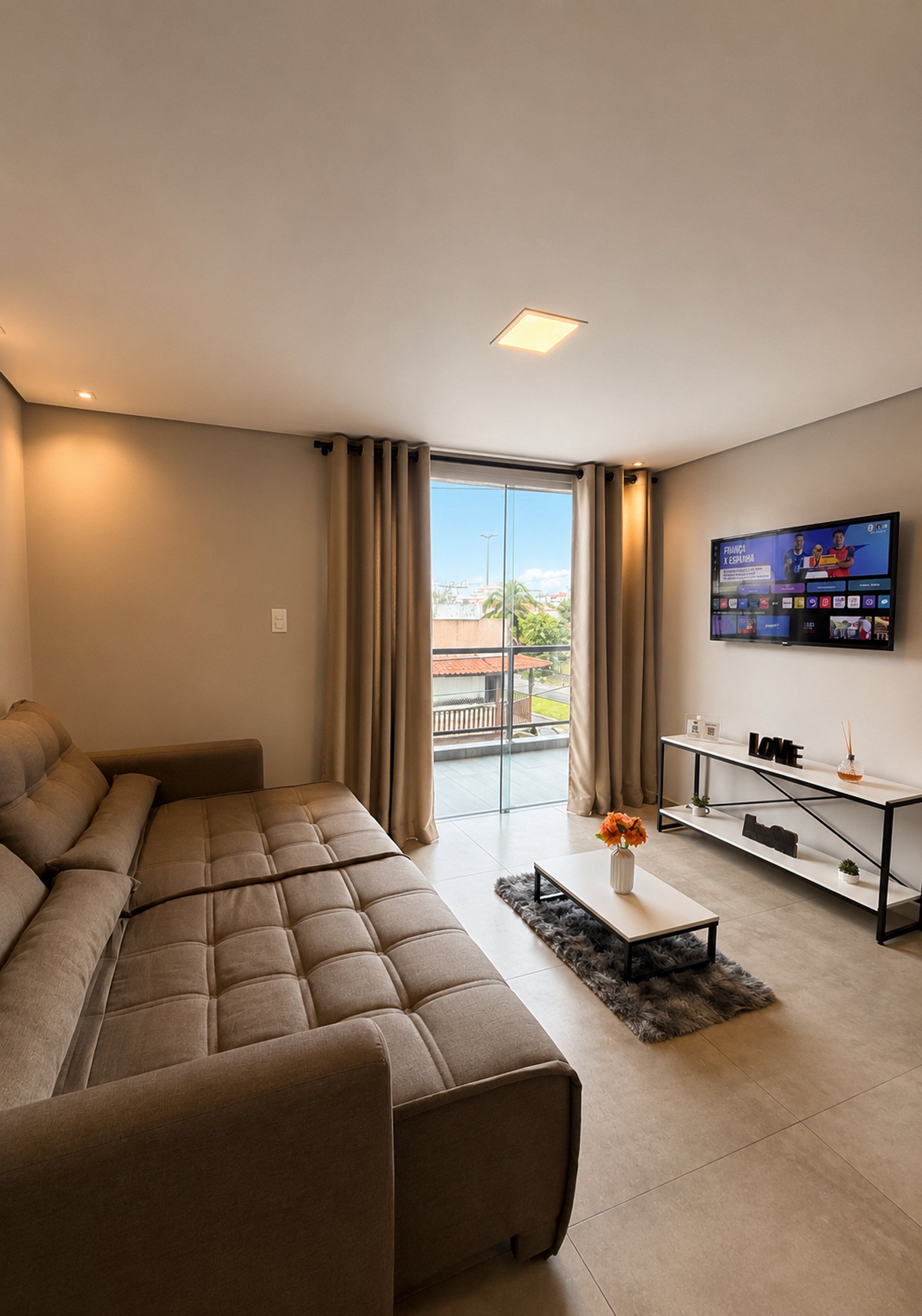 Een moderne woonkamer met een modulaire bank, een salontafel en een flatscreen televisie aan de muur.