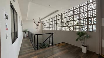 Un interior moderno con suelo de madera, barandilla de vidrio y un panel decorativo en la pared.