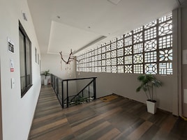 Un interior moderno con suelo de madera, barandilla de vidrio y un panel decorativo en la pared.