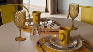 Une table de salle à manger ronde, avec des chaises jaunes, un verre décoré de motifs dorés, une tasse jaune et un verre décoré de motifs dorés, le tout posé sur un set de table.