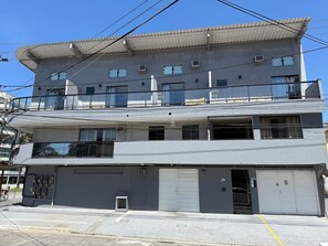 A multi-story building with a flat roof, balconies, and a garage entrance. - Loft do Braga (Cabo Frio)
