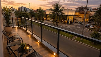 Varanda com vista para a rua e edifícios ao pôr do sol.