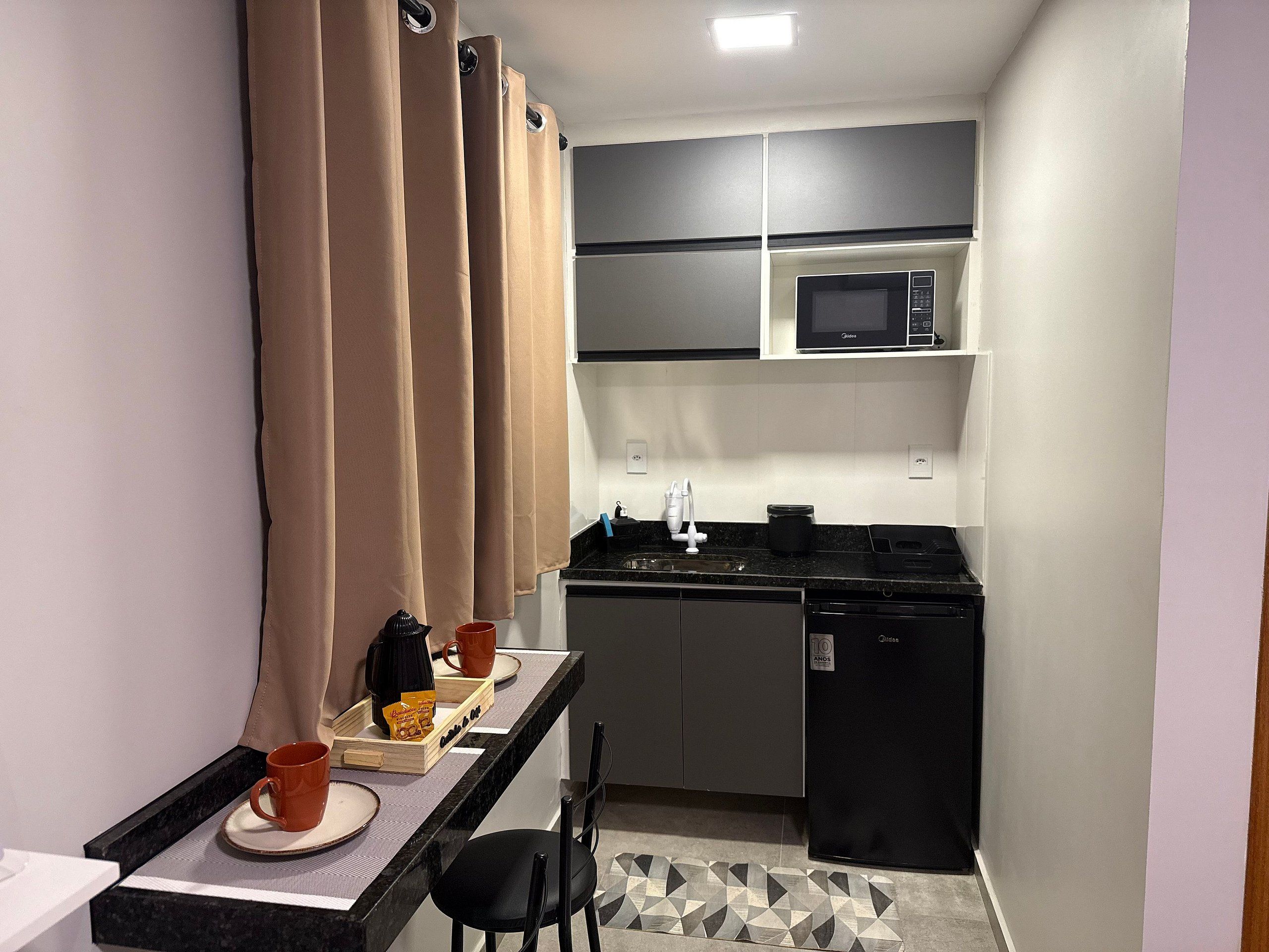 A compact kitchenette with a microwave, sink, and a small refrigerator.