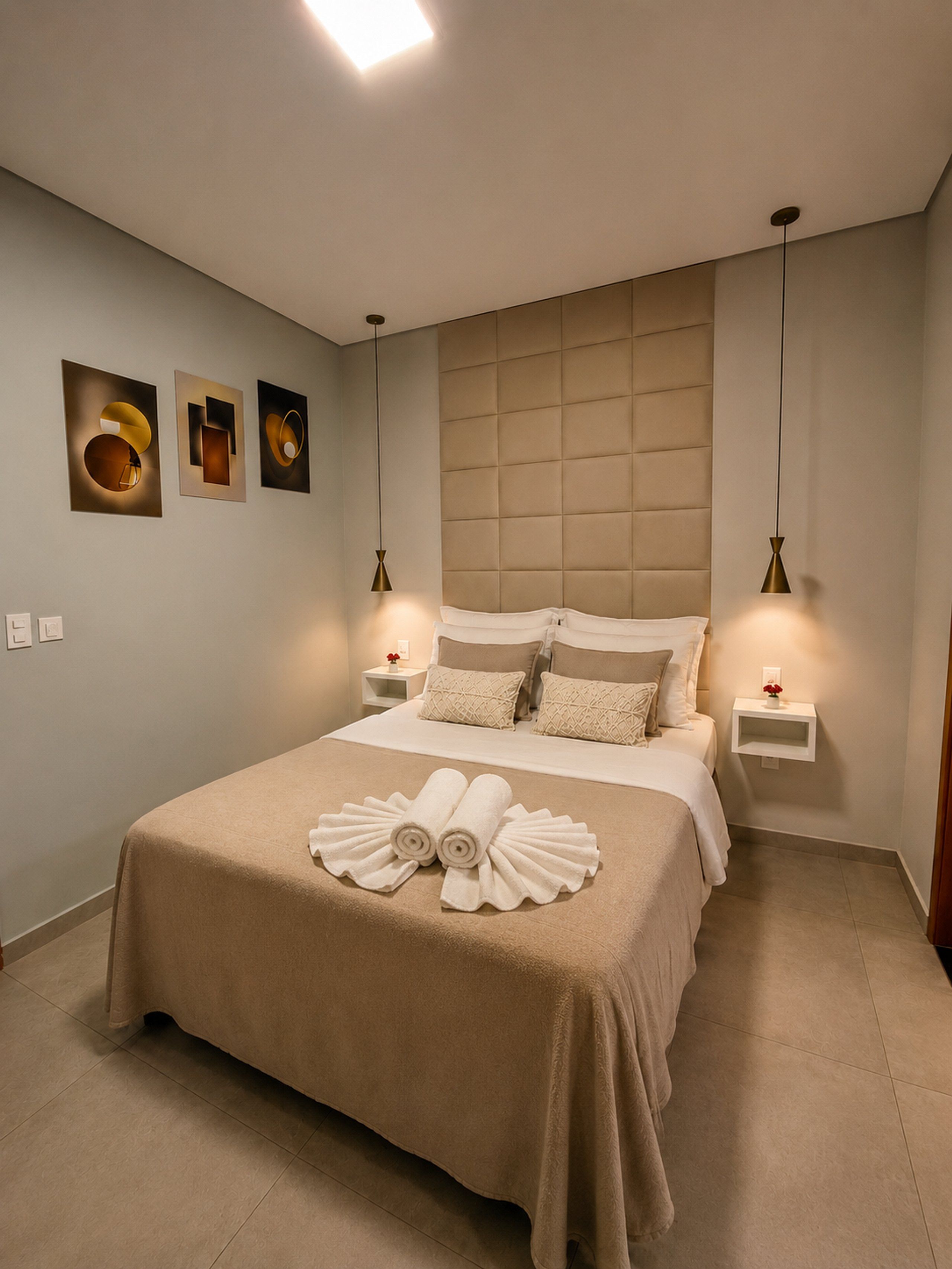 Habitación de hotel con una cama grande, dos mesitas de noche, un cabecero y una obra de arte colgada en la pared.
