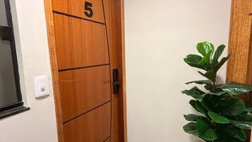Une porte en bois portant le numéro 5, un pot de fleurs et un paillasson.