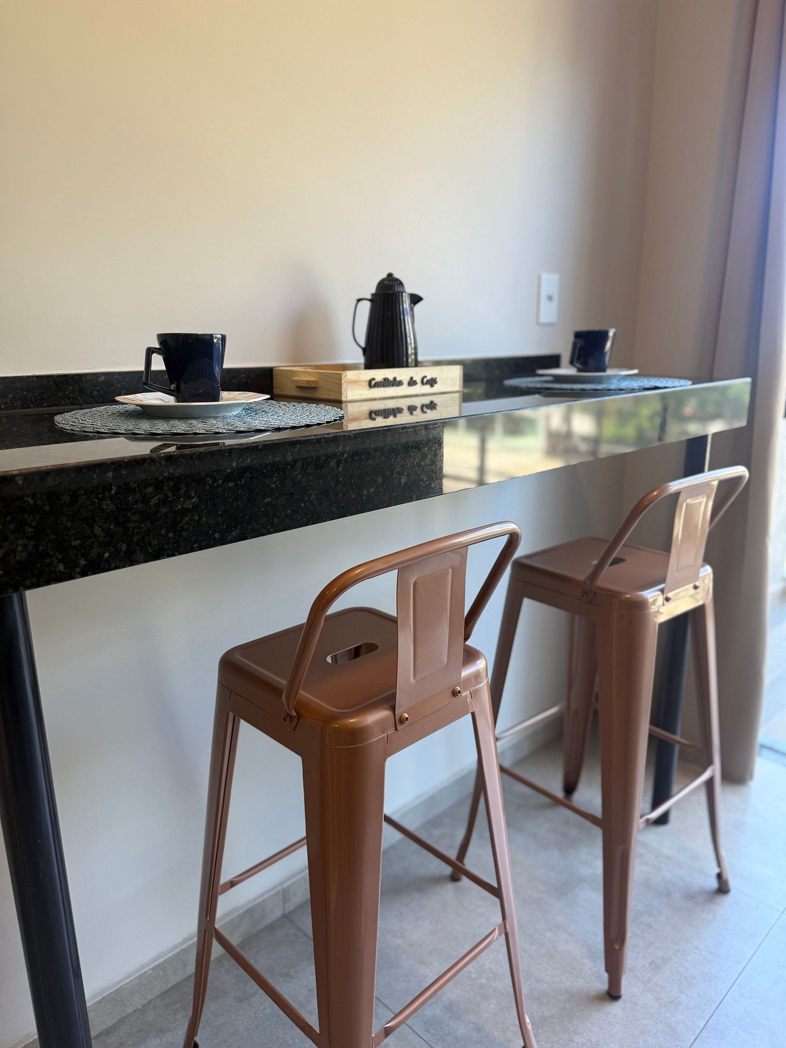 Een kitchenette met een koffiezetapparaat, twee stoelen en een houten doosje met de tekst 'Cafettina de Caffe'.