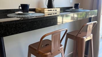 Een kitchenette met een koffiezetapparaat, twee stoelen en een houten doosje met de tekst 'Cafettina de Caffe'.