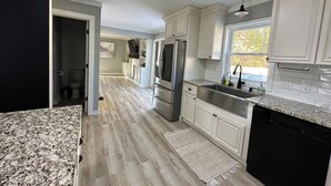 A modern kitchen with white cabinets, stainless steel appliances, and a granite countertop. - Mini gold and pool spacious 3 level floor home for 14 people  (Raleigh)