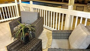 A wooden deck with wicker furniture, a pool, and string lights. - Mini gold and pool spacious 3 level floor home for 14 people  (Raleigh)