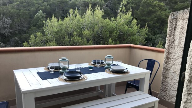 Une table blanche dressée à l’extérieur, avec des arbres en arrière-plan.