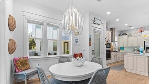 A bright kitchen with white cabinets, a round dining table with wicker chairs, and a chandelier. - Playful & Fun at Coco's~ Golf Cart, Bikes, 2 Pools PLUS Easy beach access (Inlet Beach)