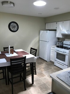 A compact kitchen with a dining area, white appliances, and a clock on the wall. - Quiet 2BR • Garage • Yard • EV Charger – Eureka (Eureka)