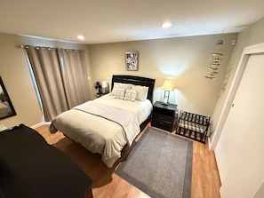 A bedroom with a bed, bedside tables, a desk, a chair, a rug, curtains, and a wall-mounted shelf. - Quiet 2BR • Garage • Yard • EV Charger – Eureka (Eureka)
