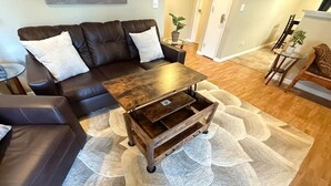 A living room with a dark brown leather sofa, a wooden coffee table, and a patterned rug.