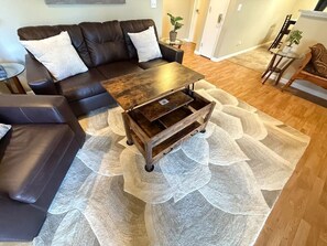 A living room with a dark brown leather sofa, a wooden coffee table, and a patterned rug. - Quiet 2BR • Garage • Yard • EV Charger – Eureka (Eureka)