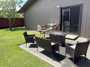 A patio with wicker furniture, a grill, and a glass-top table.
