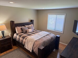 A bedroom with a bed, bedside tables, a lamp, a window with blinds, and a TV. - Quiet 2BR • Garage • Yard • EV Charger – Eureka (Eureka)