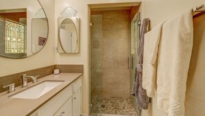 Une salle de bain avec deux lavabos, un miroir, un porte-serviettes et un espace douche.