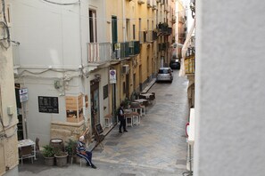 A narrow street with buildings, outdoor seating, and a parked car. - Centromare Trapani (Trapani)