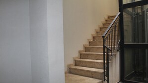 A staircase with beige steps and a black railing leading to a glass door. - Centromare Trapani (Trapani)