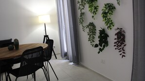 A dining area with a wooden table, black chairs, a lamp, and a wall decorated with various plants. - Centromare Trapani (Trapani)