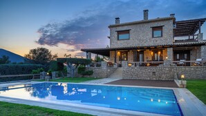 A stone house with a swimming pool, outdoor seating, and a view of the mountains. - Villa Vicanti: Private Paradise (Mesochori)