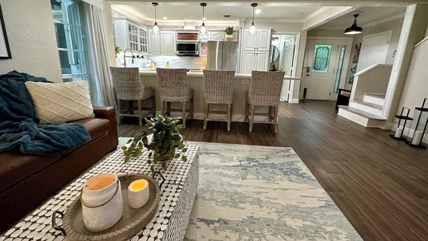 Una cocina moderna con armarios blancos, una isla central con taburetes altos e iluminación colgante.