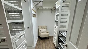 Un armario vestidor con estantes integrados, un sillón y una puerta.