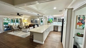 Una cocina amplia con una isla central, armarios blancos y un comedor con sofá y sillas.