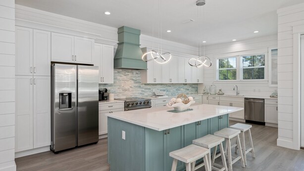 A modern kitchen with white cabinetry, a central island with bar stools, stainless steel appliances, and a stone backsplash. - NEW - Symphony! Sleeps 18! Pool! Golf Cart (Santa Rosa Beach)