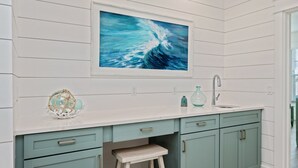 A kitchen with a white countertop, teal cabinets, a sink, and a framed painting of a wave. - NEW - Symphony! Sleeps 18! Pool! Golf Cart (Santa Rosa Beach)