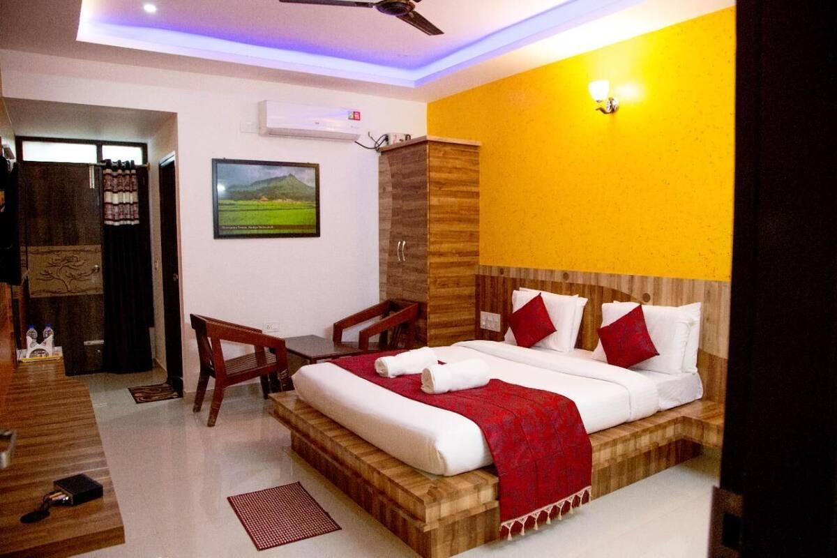 A hotel room with a bed, a desk, and a chair. There is a picture on the wall and a window.