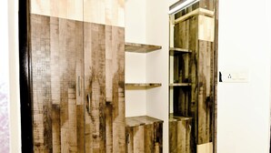 Une salle de bain avec un meuble-lavabo en bois, un miroir et une étagère fixée au mur.