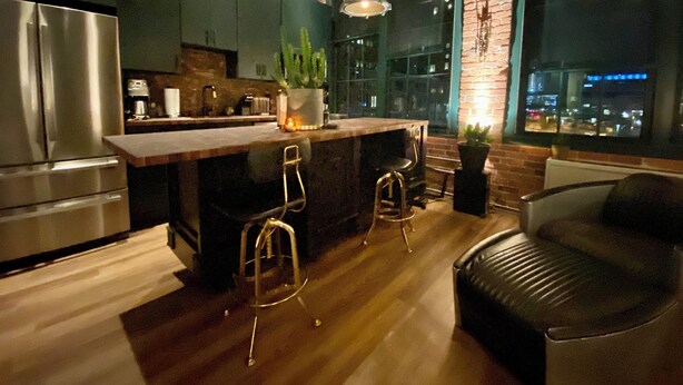 Een moderne keuken met een bar, roestvrijstalen apparatuur en een groot raam met uitzicht op de stad.