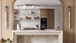 Una cocina con encimera de mármol, chimenea de ladrillo y armarios de madera.