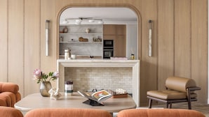 Una sala de estar moderna con chimenea, un comedor y una cocina visible a través de un arco.