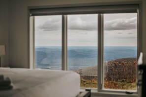 A room with a large window offering a view of a mountainous landscape.