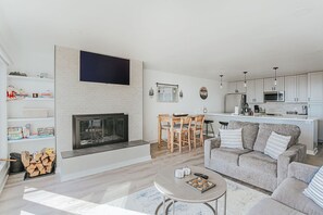 Ein modernes Wohnzimmer mit Kamin, Essbereich und Küche.