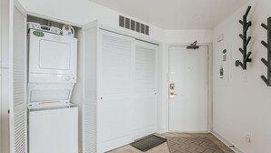 A hallway with a white laundry room, a closed door, and a wall-mounted coat rack. - Mountain View Vista: Resort Condo w/ Views (Wintergreen Resort)