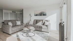 Un salon moderne avec deux canapés gris, une table basse ronde et un tapis à motifs.