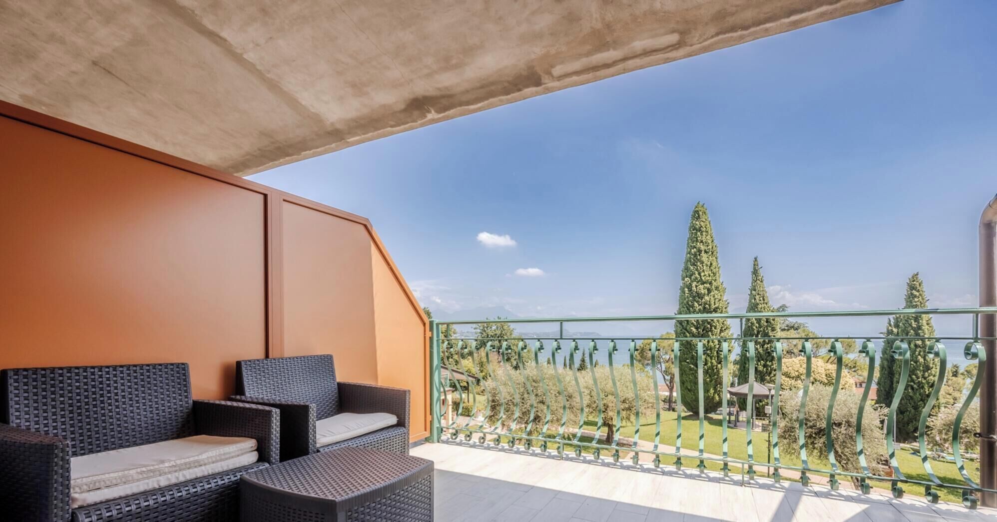 A balcony with wicker furniture, a view of trees and a distant landscape.