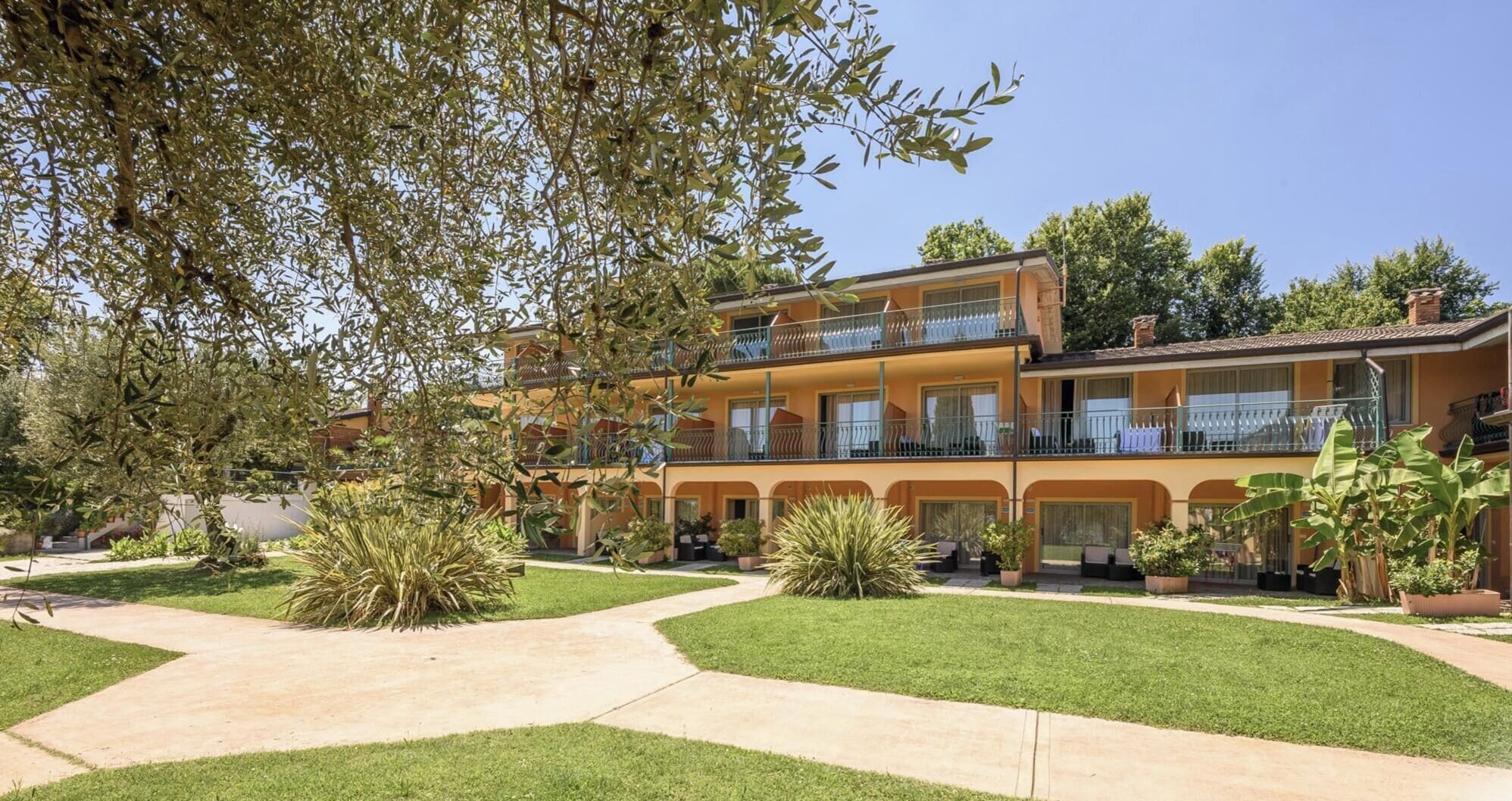 A multi-story hotel with a courtyard, outdoor seating, and a well-maintained garden.