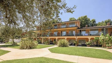 A multi-story hotel with a courtyard, outdoor seating, and a well-maintained garden.