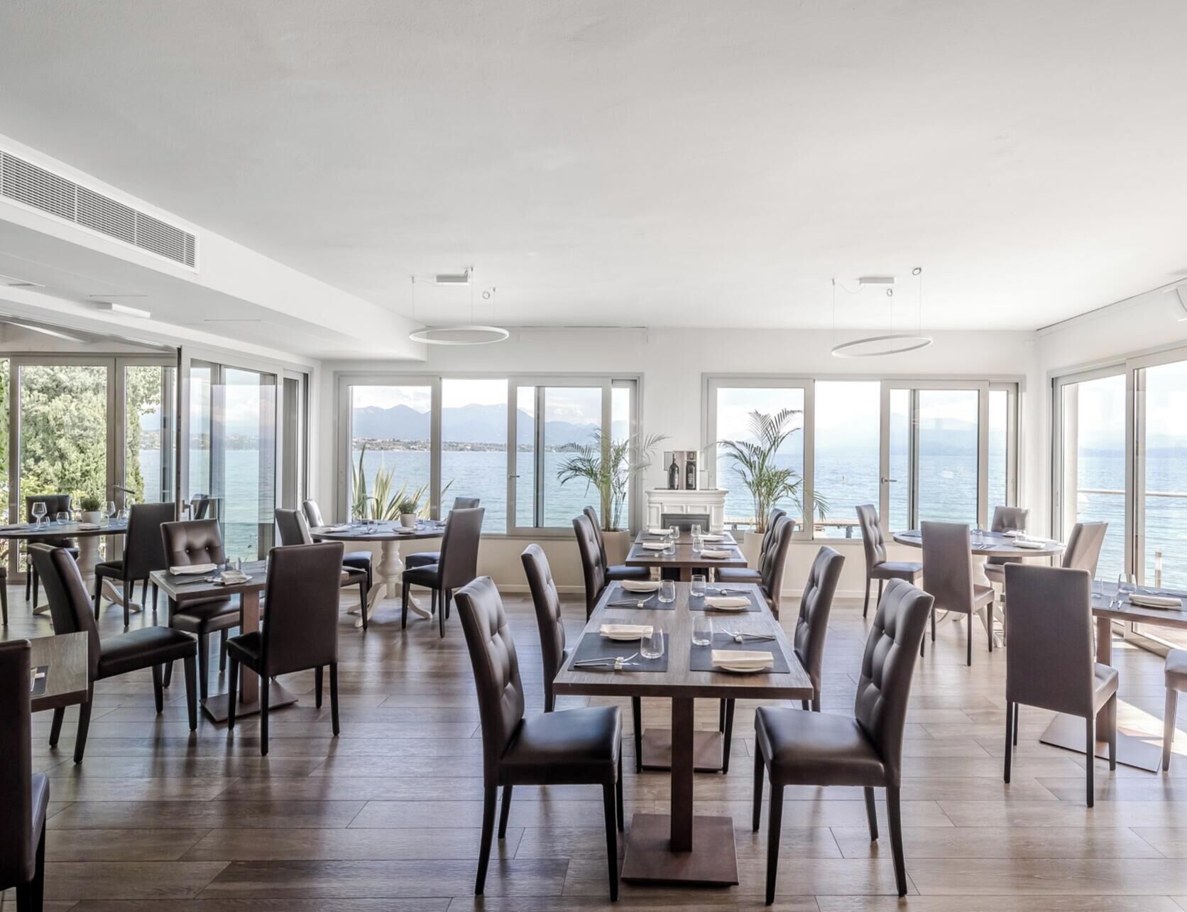A spacious dining area with large windows offering a view of the sea and mountains.
