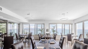 Un amplio comedor con ventanas grandes que ofrecen vistas al mar y a las montañas.