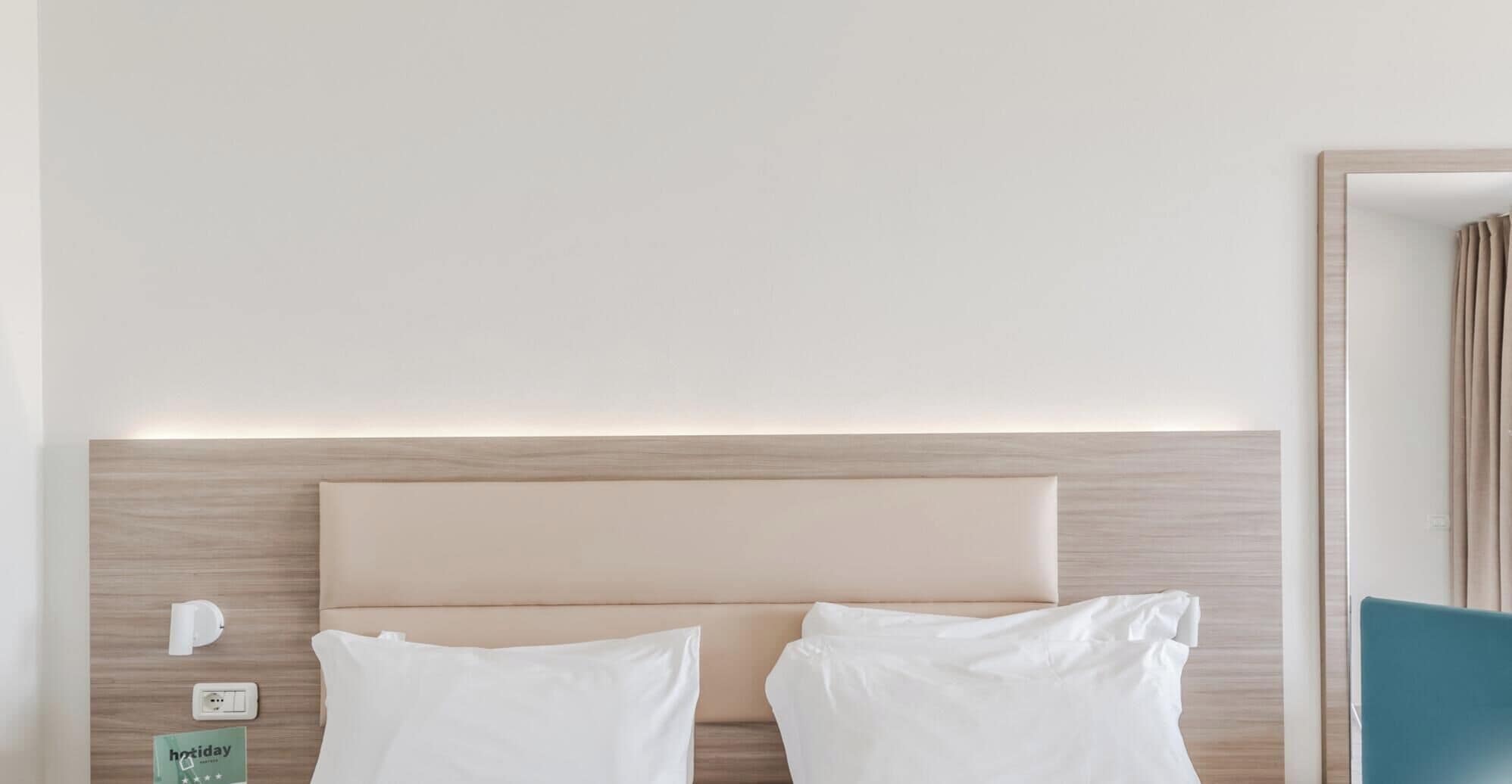 Ein Hotelzimmer mit einem Bett, einem Nachttisch, einer Steckdose und einem Schild, das einen Urlaubsrabatt anzeigt.